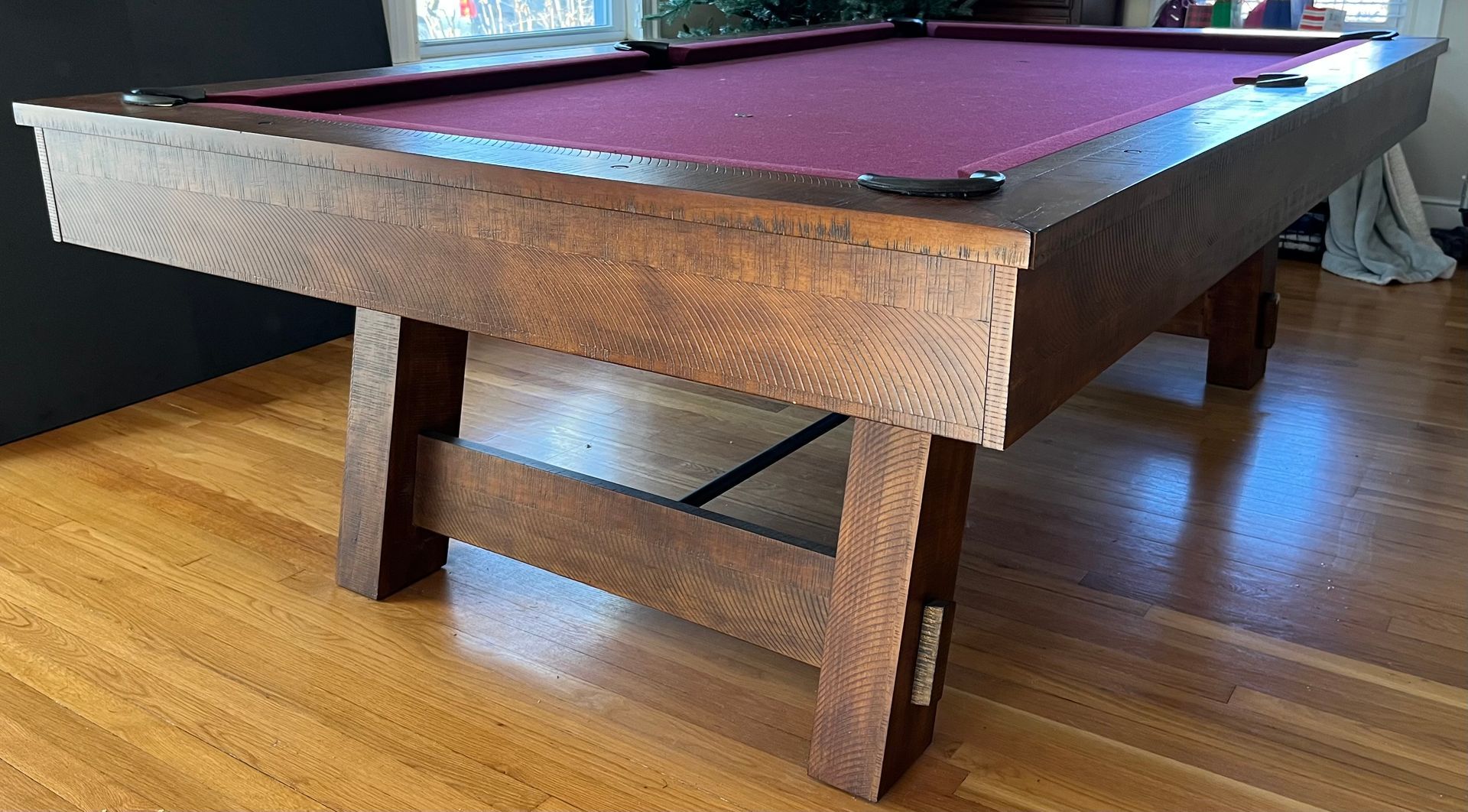 Wooden pool table with purple felt, set in a room with hardwood floors.
