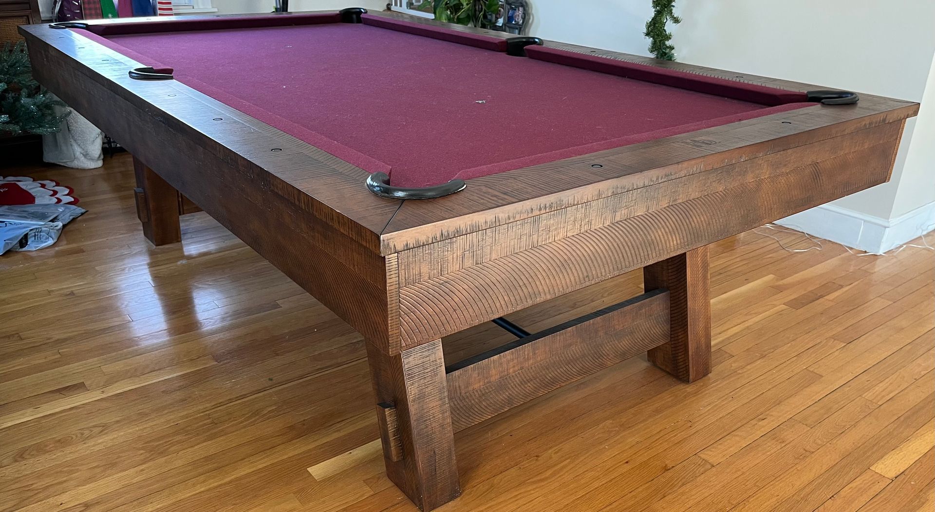 Pool table with burgundy felt, dark wood frame, and hardwood floor.