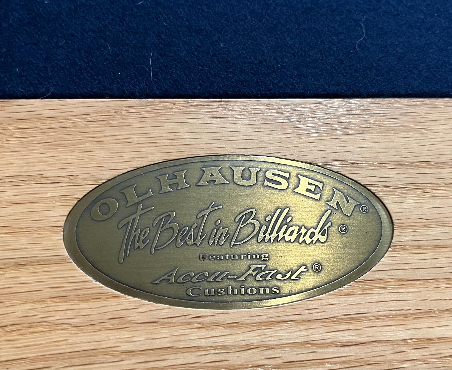 Pool table with a blue felt top and light wooden frame, in an indoor setting.