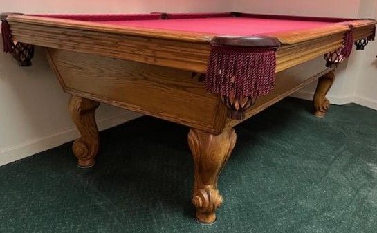 A pool table is sitting on a green carpet in a room.