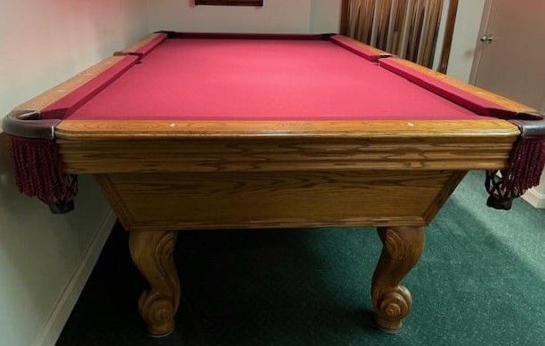A pool table with a red cloth in a room
