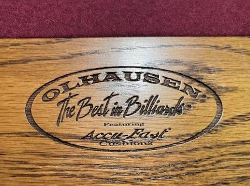 A close up of a wooden sign that says olhausen the best in billiards