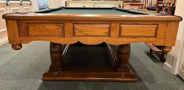 Wooden billiard table with green felt and carved base in a game room