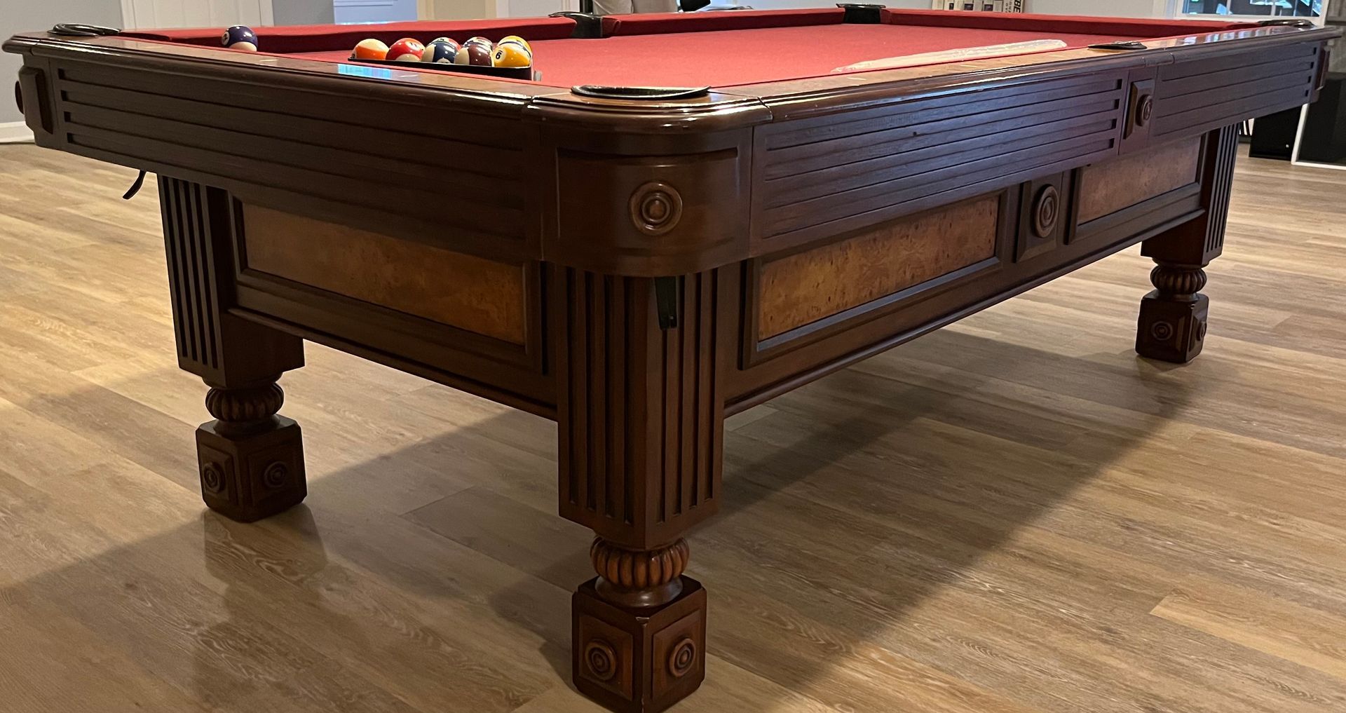 Dark wooden billiard table with red felt in a room on a wood floor