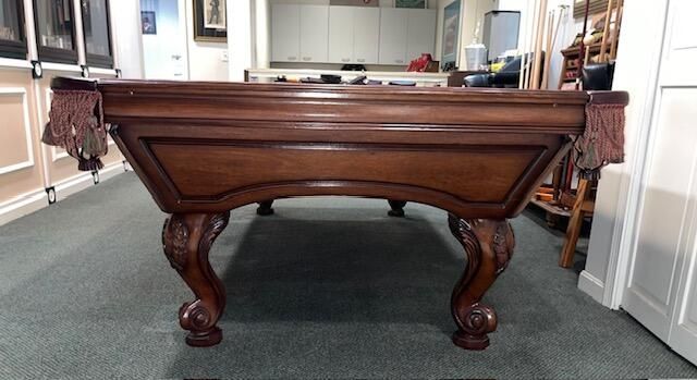 Wooden pool table with green felt, in a room.