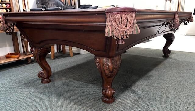 Wooden pool table with green felt, in a room