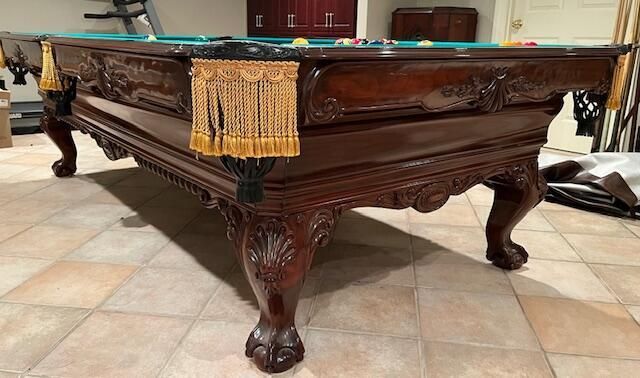 A pool table is sitting on a tile floor in a living room.