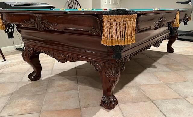 A pool table is sitting on a tile floor in a living room.