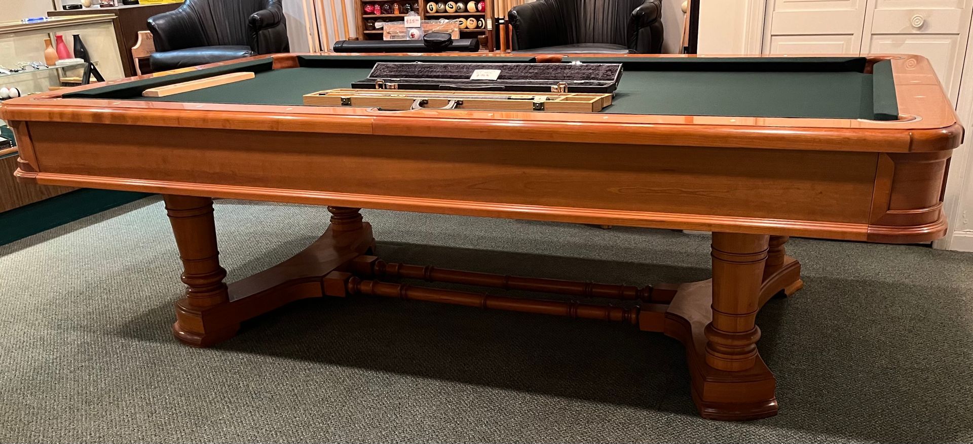 Wooden pool table with blue felt, in a room.