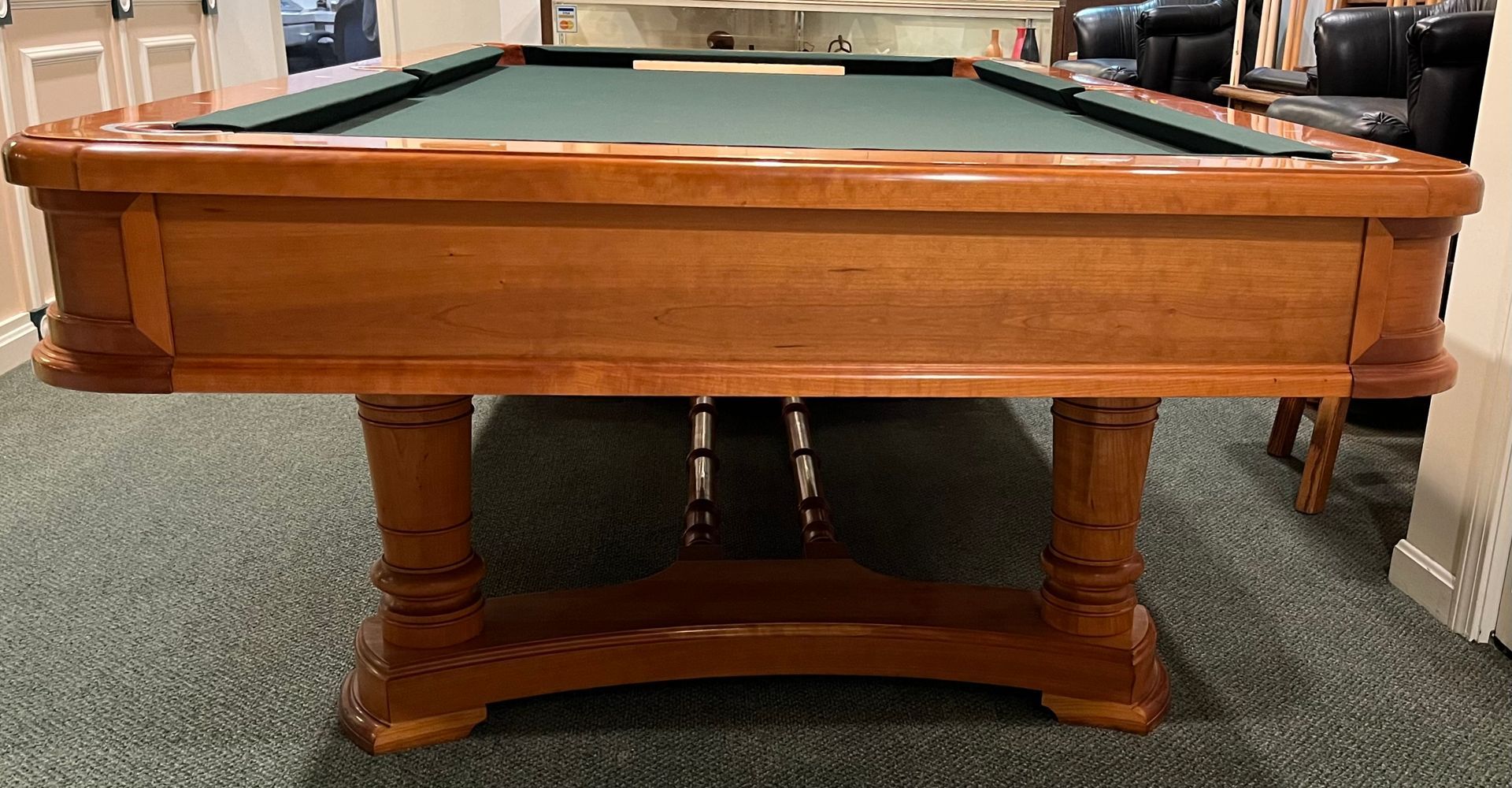 Wooden pool table with blue felt, in a room with concrete floor.
