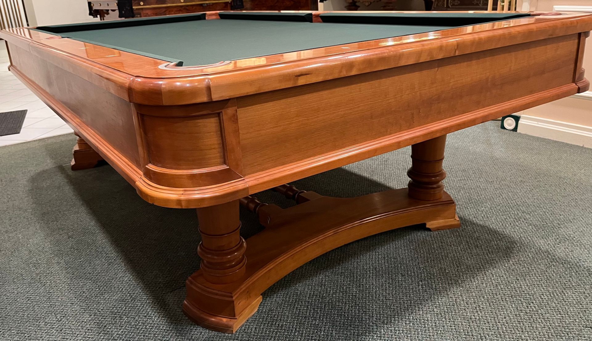 Wooden pool table with blue felt, in a room with a brick fireplace.