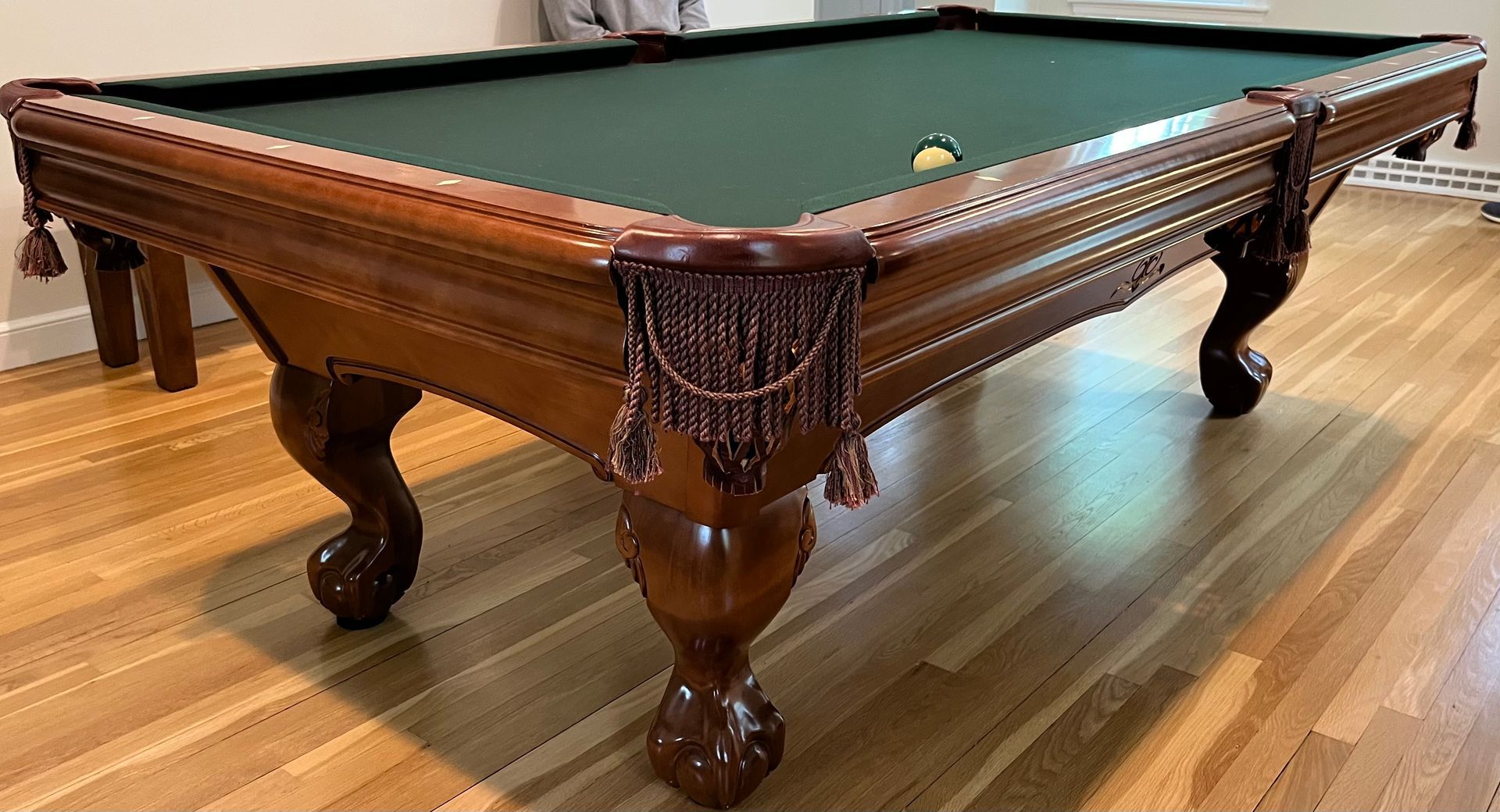 Wooden pool table with green felt and carved legs in a polished room