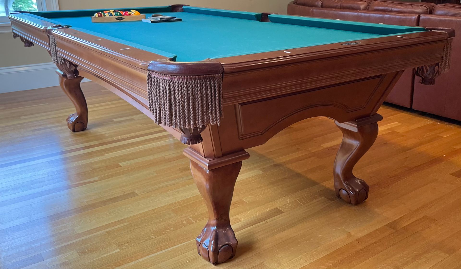 Wooden billiards table with green felt and carved legs in a game room