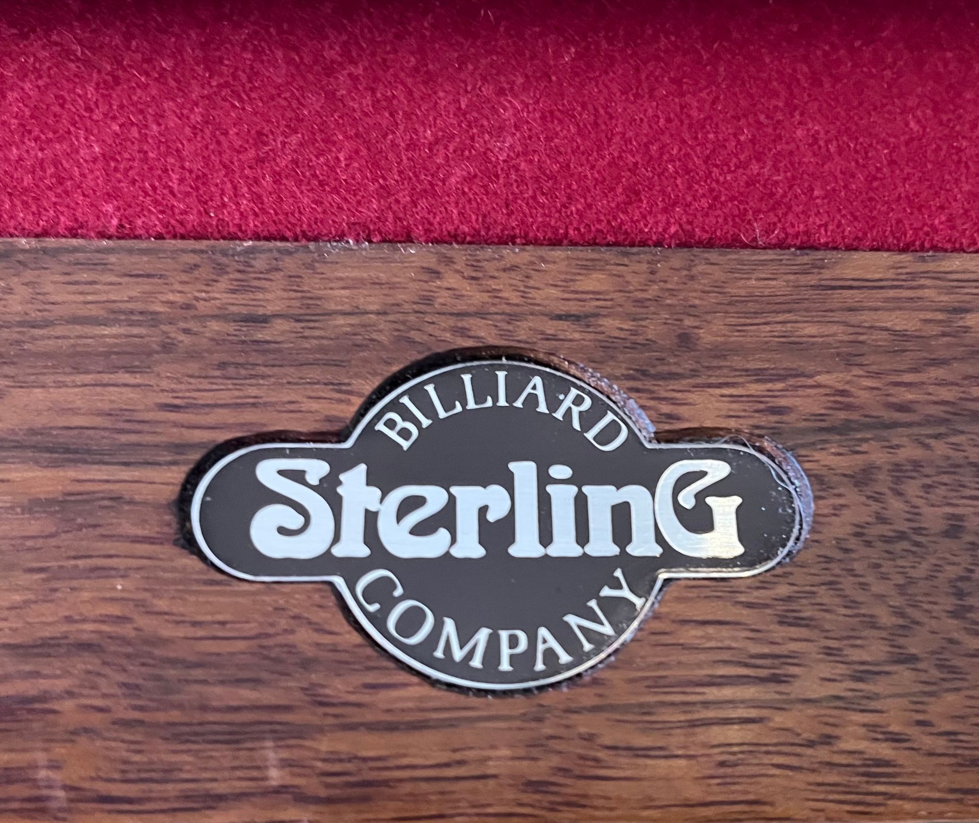 Sterling Billiard Company logo on a wooden pool table with red felt.