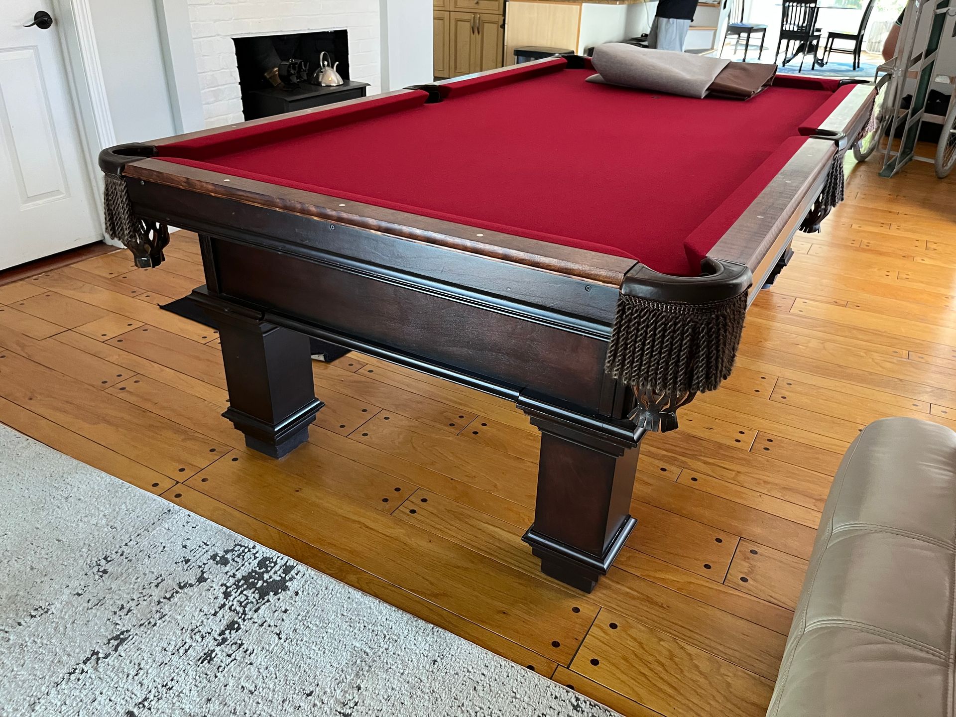 Dark wood pool table with red felt, in a room with wooden floors.