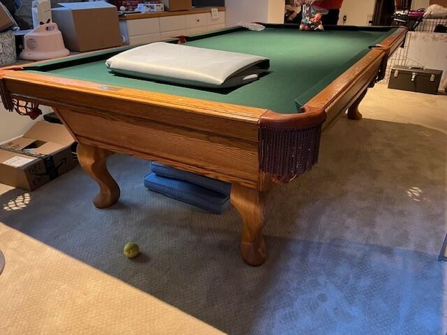 Pool table with green felt, wooden frame, and fringe