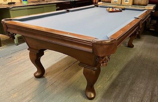 Pool table with blue felt, brown wood frame and legs