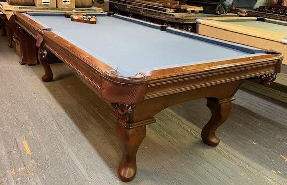 Wooden pool table with a light blue felt surface and carved legs