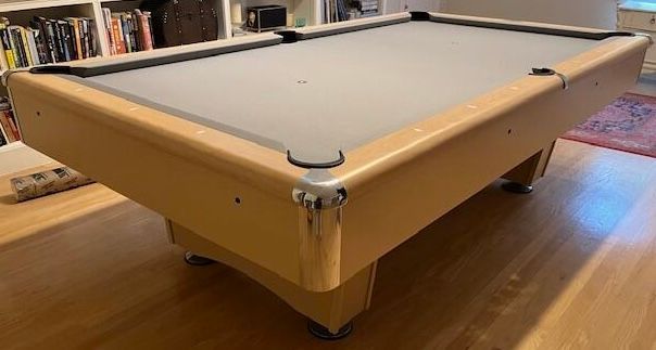 Pool table, light wood, grey felt, in a room.