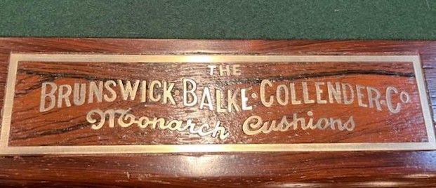 A wooden pool table nameplate reading 