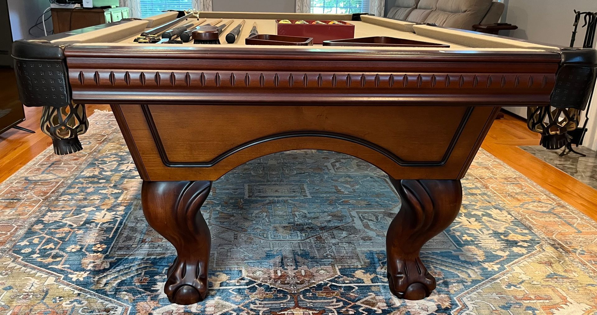 Ornate wooden pool table with carved legs on a patterned rug in a room