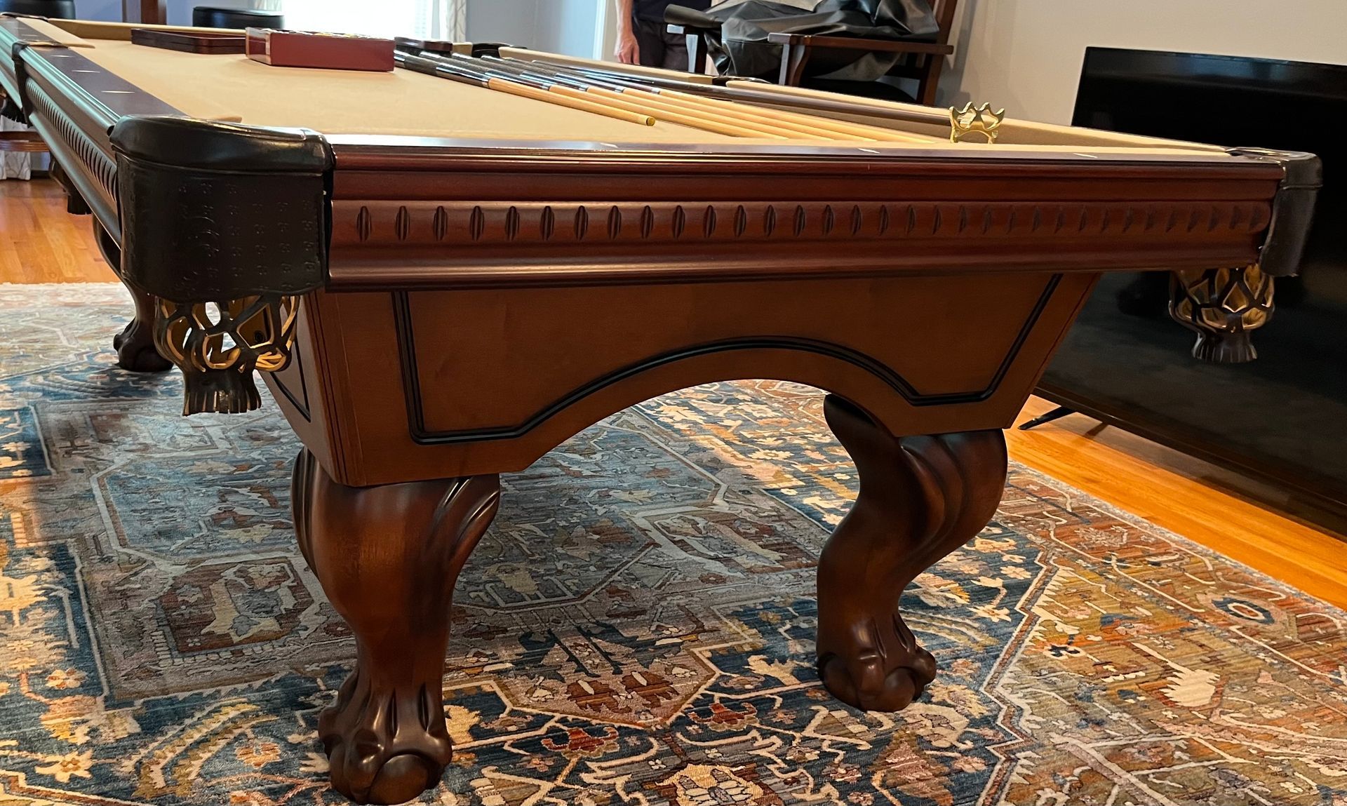 Brown carved wooden pool table on a patterned rug in a room