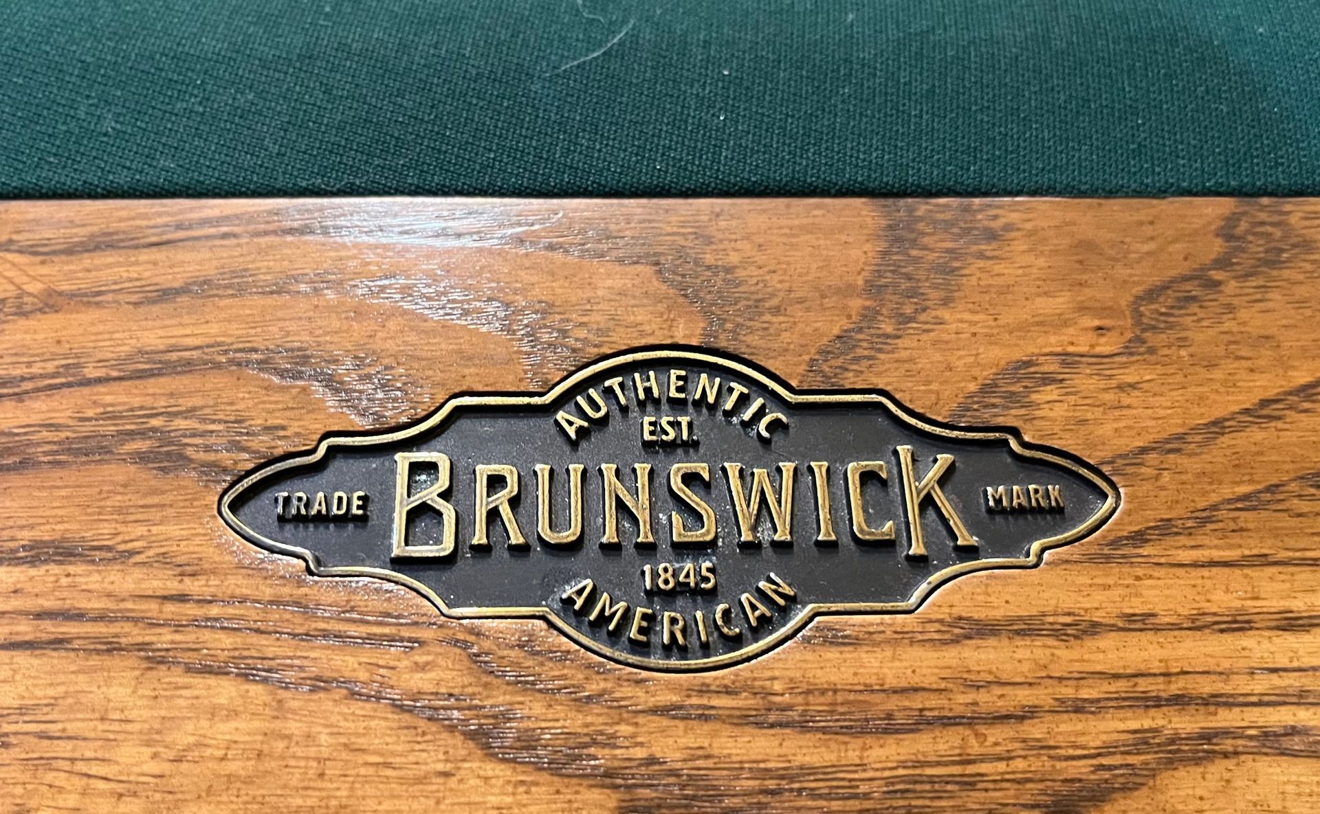 Brunswick logo plaque on a wood-grain surface with green felt background