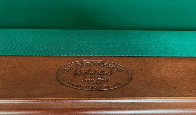 Green and brown felt-lined wooden case with an oval embossed emblem on the lid