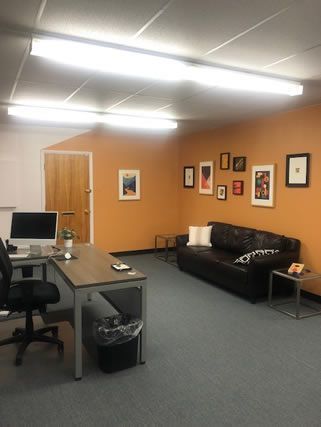 A living room with a couch , desk , chair and computer.