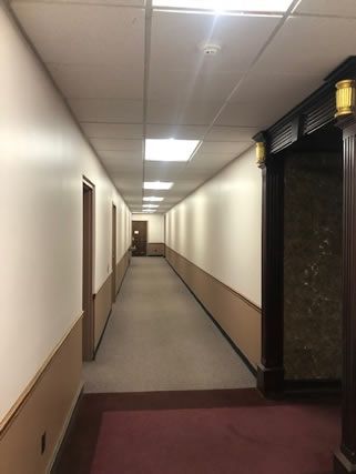 A long hallway with white walls and a red carpet
