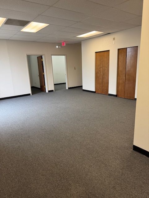An empty room with a carpeted floor and wooden doors