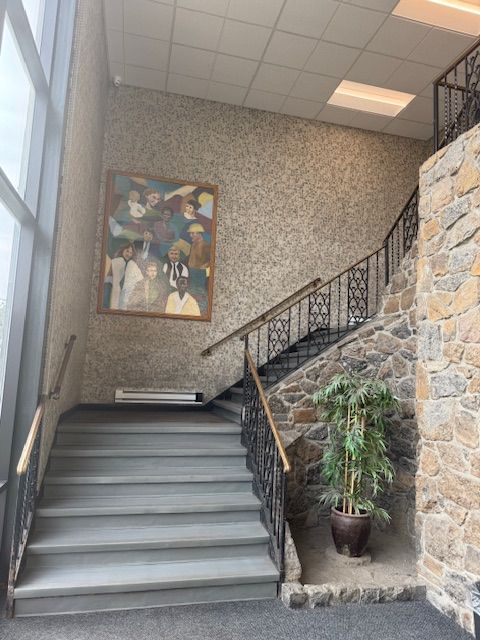 A staircase in a building with a painting on the wall above it.