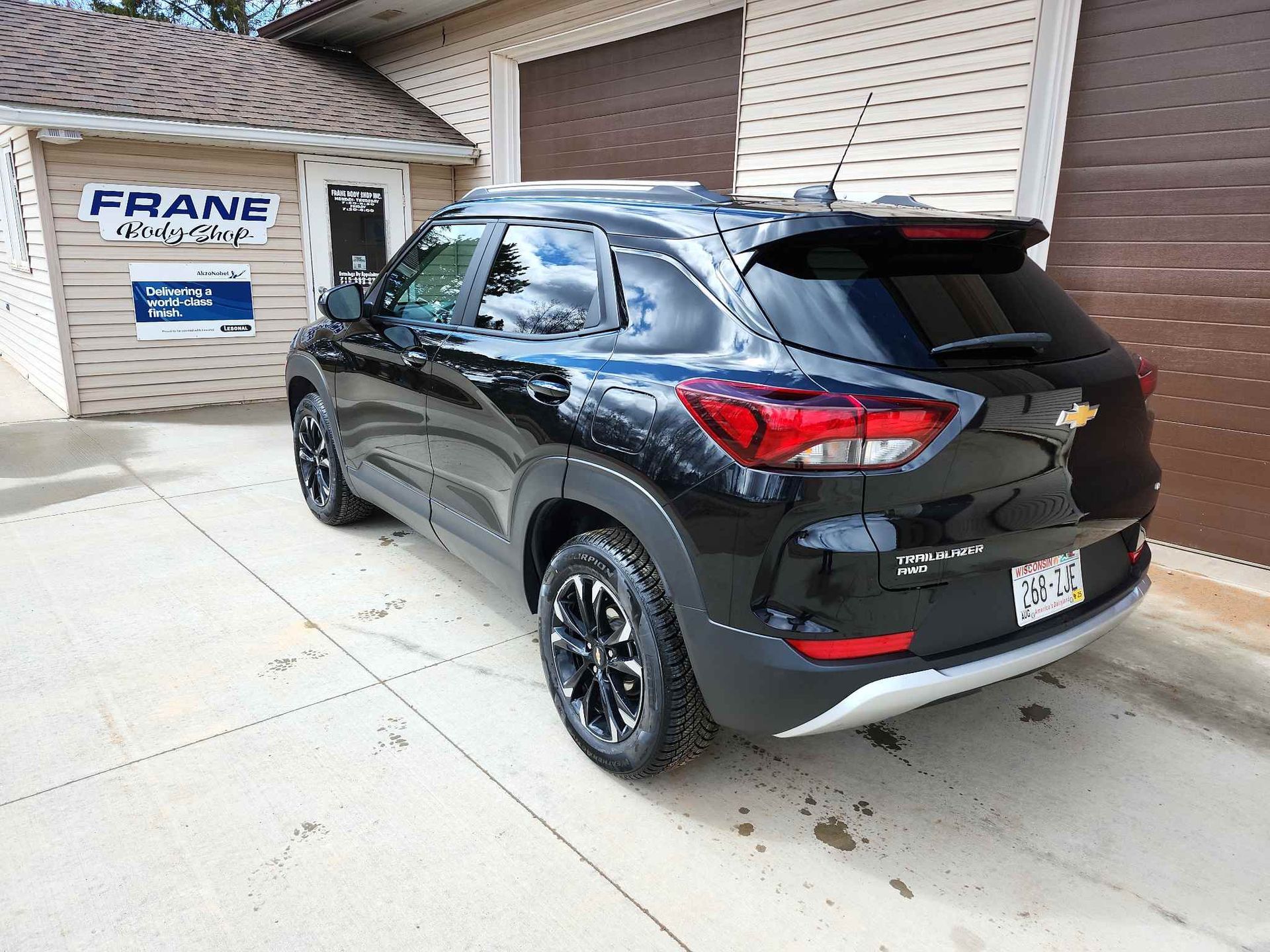 A black chevrolet trailblazer is parked in front of a garage.