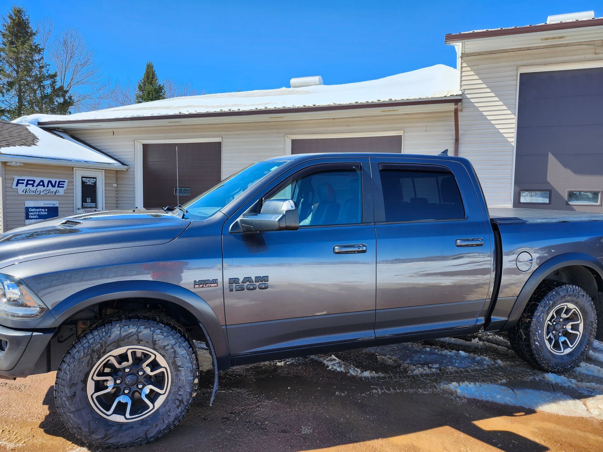 A gray ram truck is parked in front of a building.