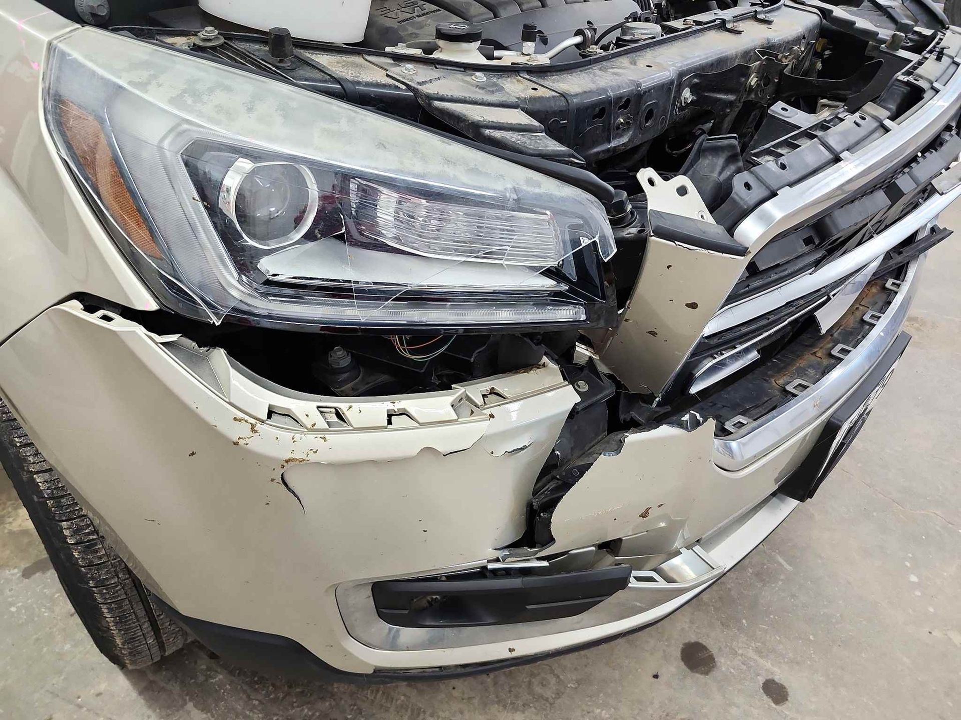 A close up of a damaged car with the hood open.