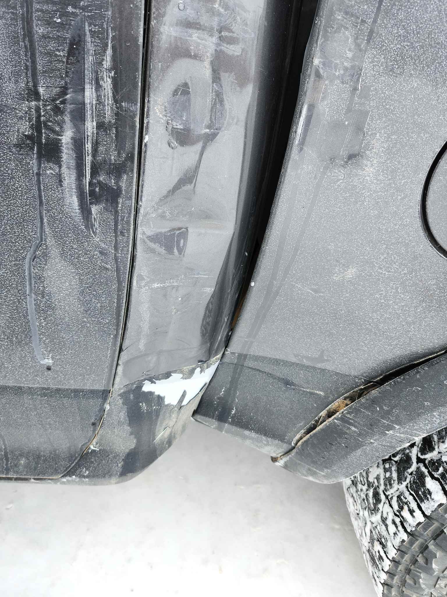 A close up of a car's fender in the snow.
