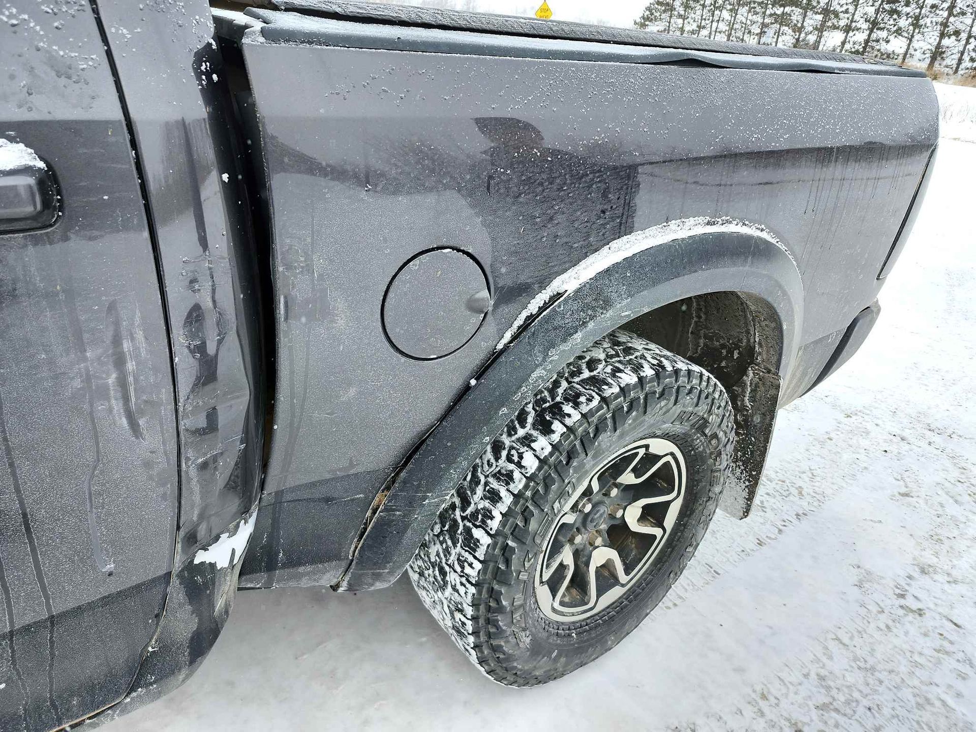 A black truck is parked in the snow on a snowy road.