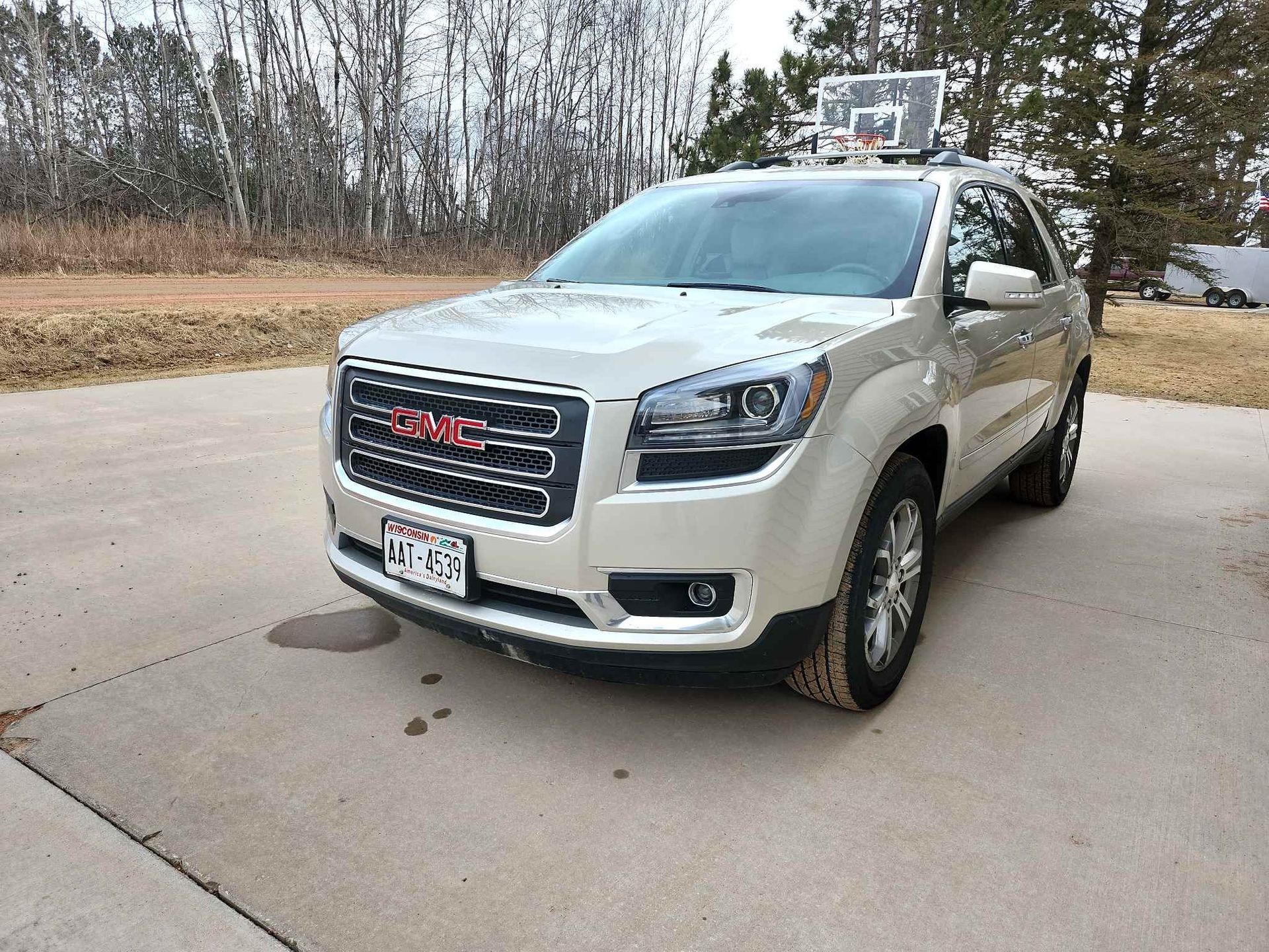 A white GMC Acadia is parked in a driveway.