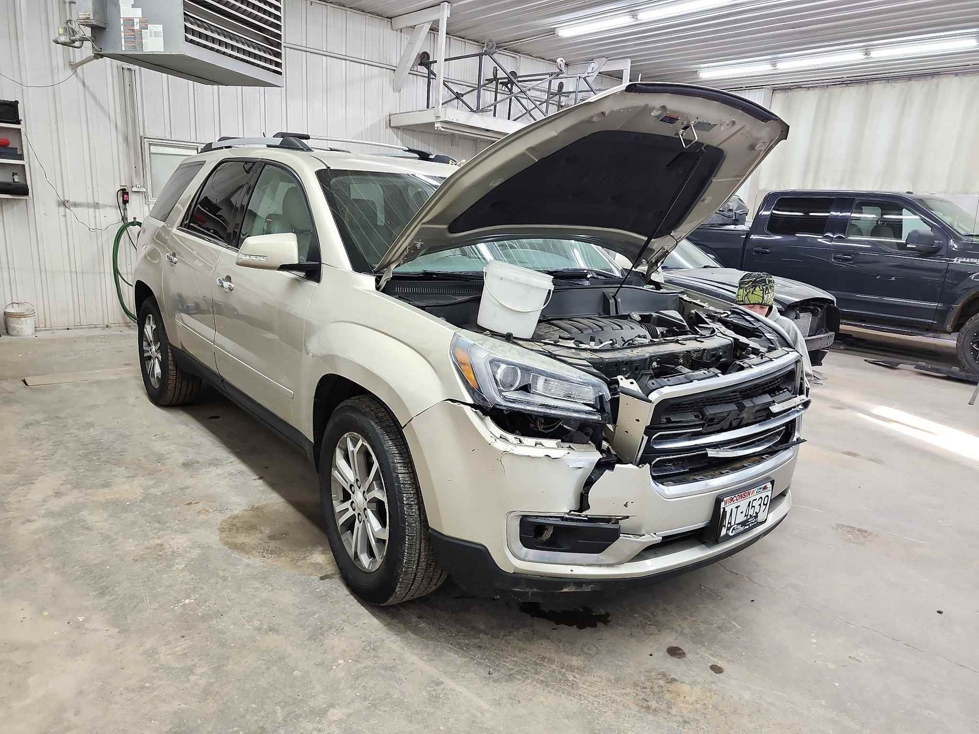 A car with its hood up is parked in a garage.
