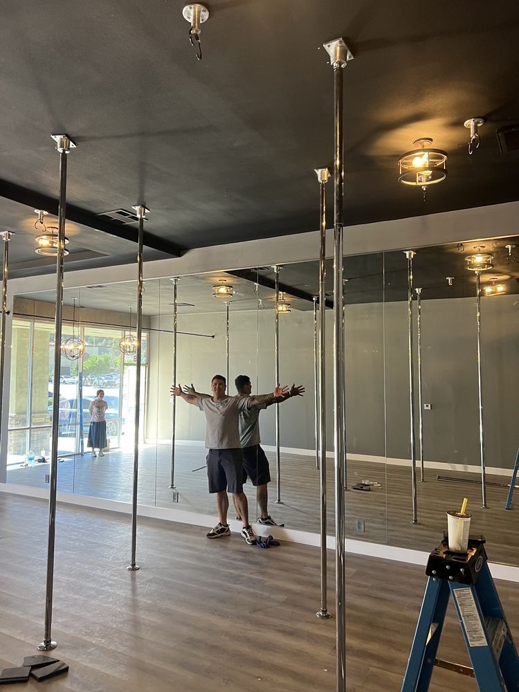 Two men are standing in a room with poles and mirrors.