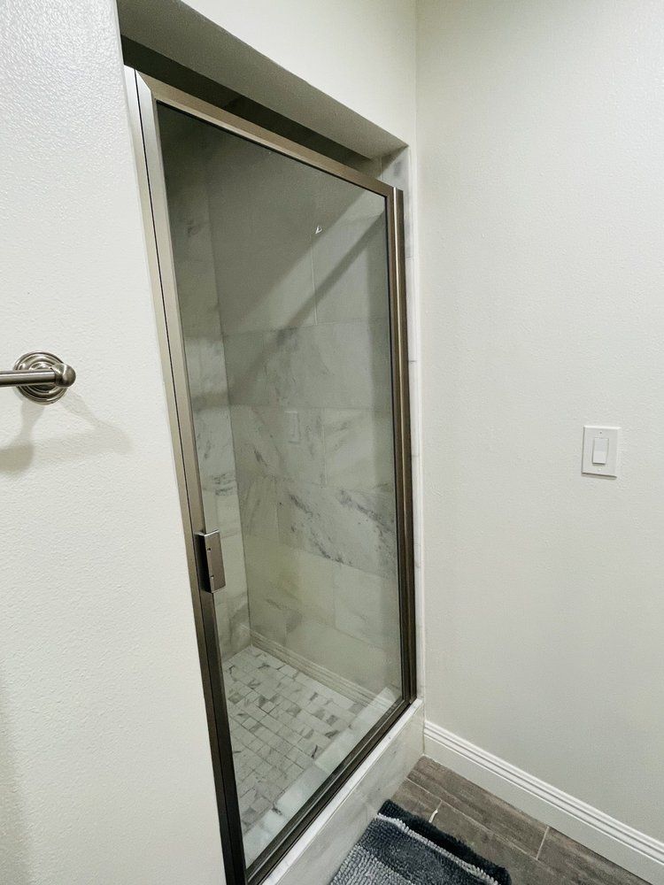 A bathroom with a glass shower door and a towel rack.