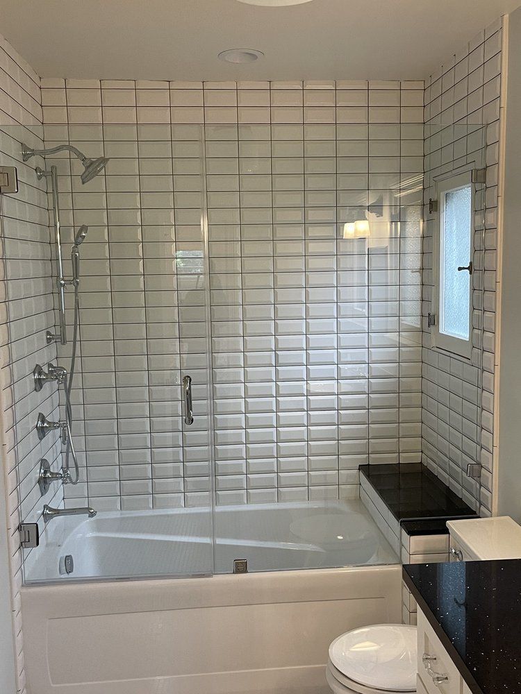 A bathroom with white tiles , a tub , a toilet and a shower.
