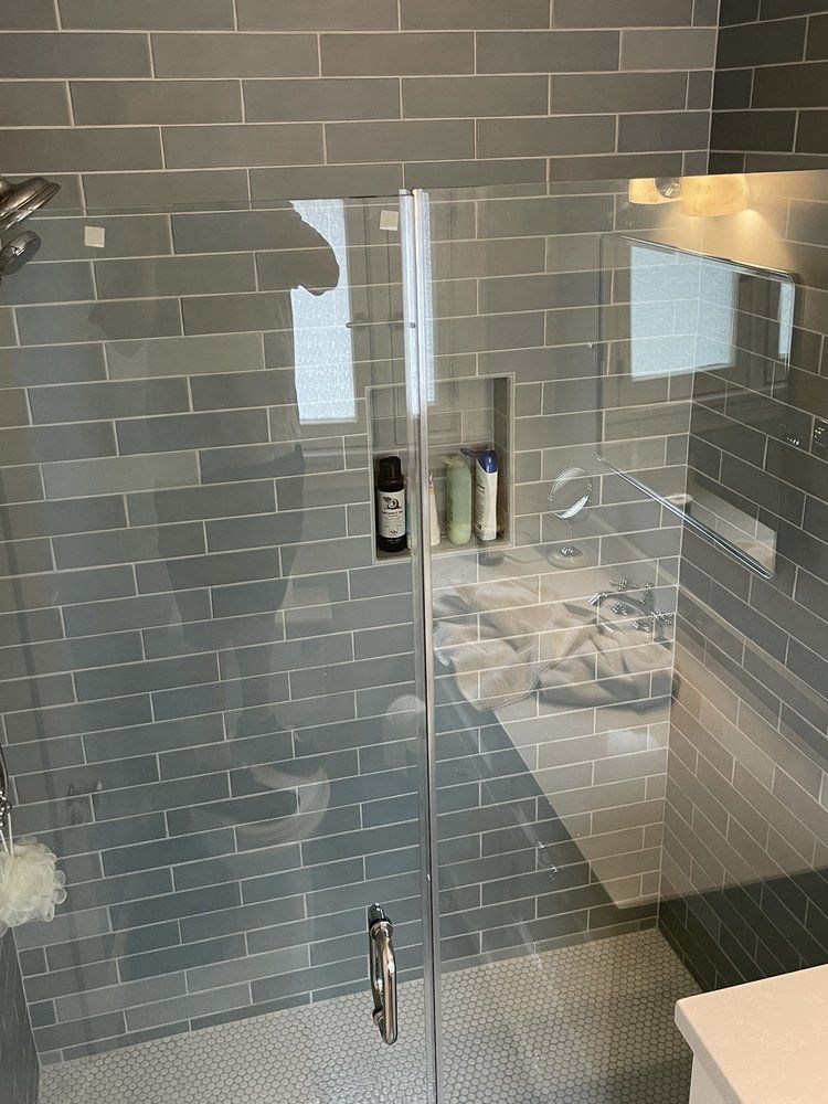 A bathroom with a walk in shower with a glass door.