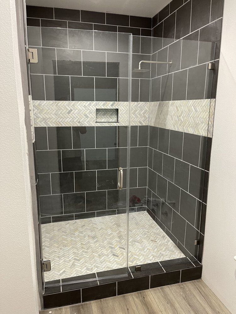 A bathroom with black and white tiles and a walk in shower with a glass door.