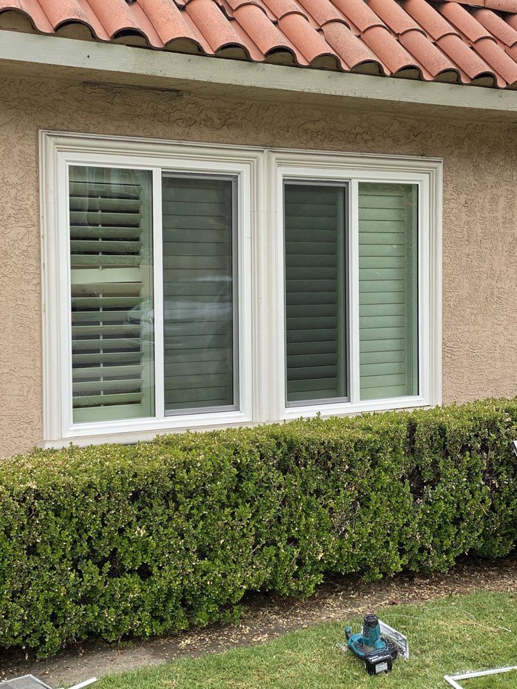 A house with two windows and a sprinkler in front of it