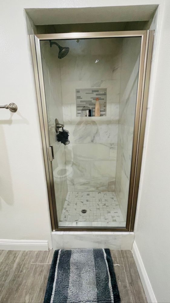 A bathroom with a walk in shower and a rug on the floor.