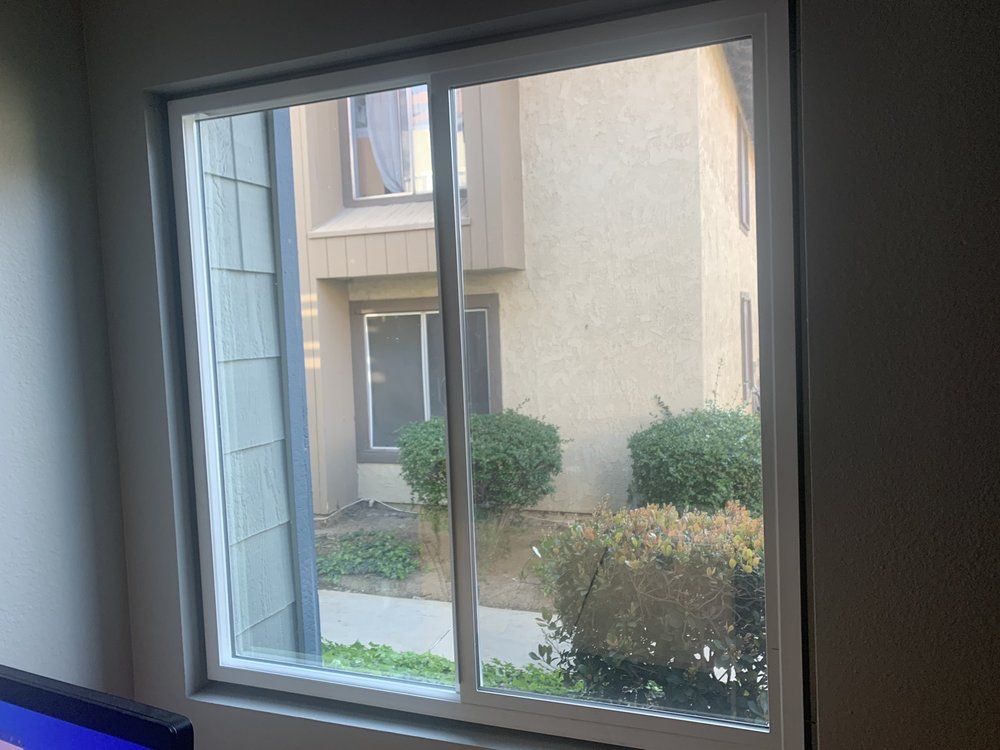 A window with a view of a house and a sliding glass door.