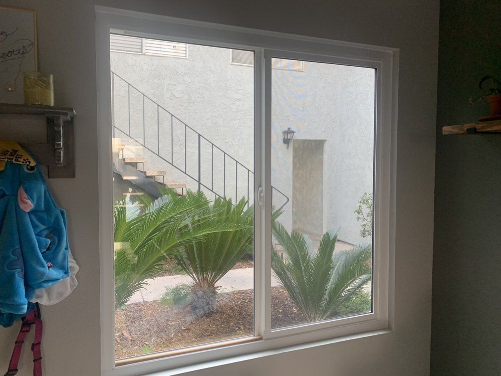 A large window in a room with a view of a staircase and palm trees.