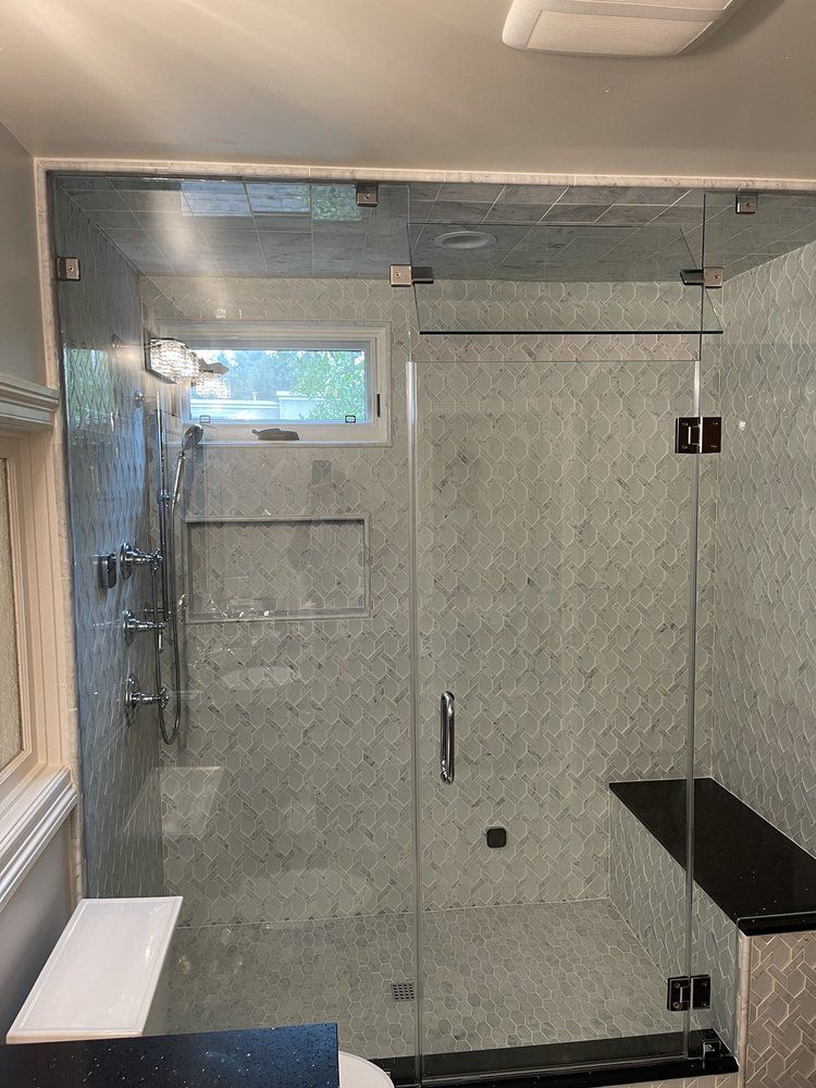 A bathroom with a glass shower door and a window.