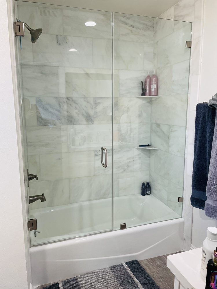 A bathroom with a bathtub and a shower with a glass door.